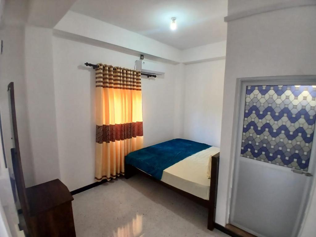 a small bedroom with a bed and a curtain at AMM Rooms in Nikawatawana