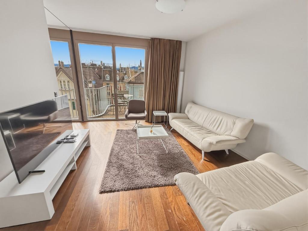 a living room with white furniture and a large window at Comfortable 1BR flat at great location - Baron 44 in Zurich
