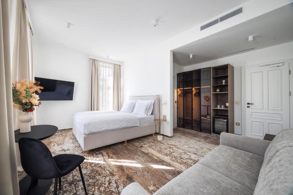 a white bedroom with a bed and a couch at Hiša F5 in Ljubljana