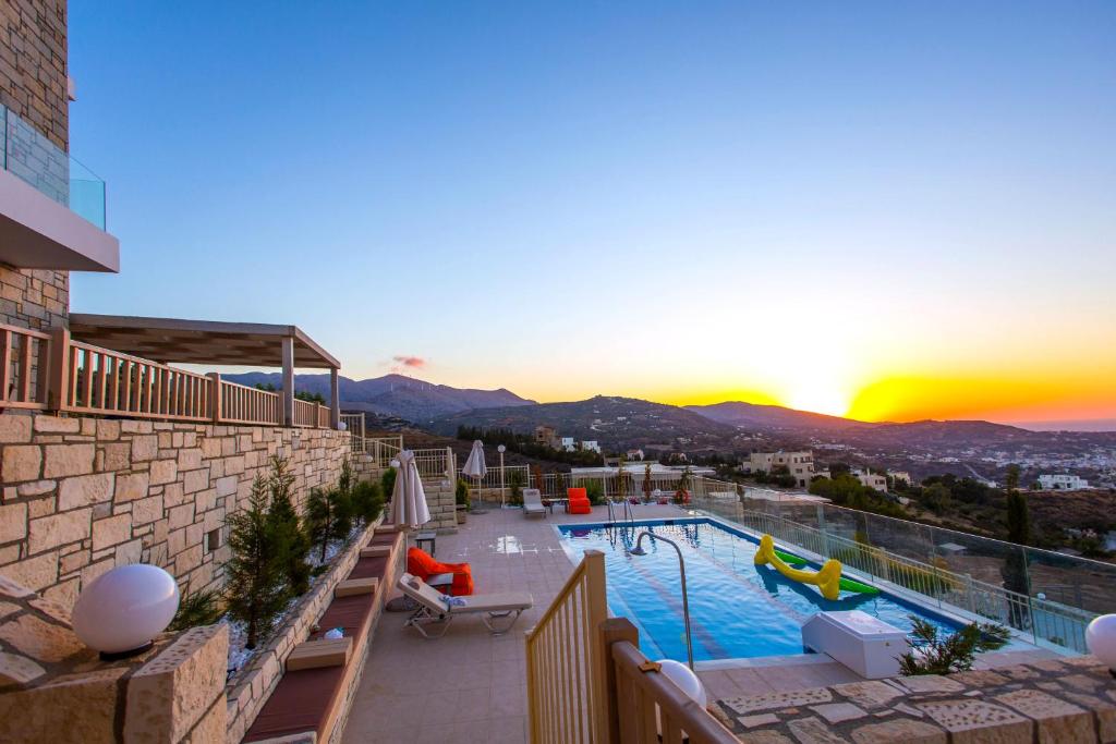 uitzicht op een zwembad op een gebouw met zonsondergang bij Dilira Villas in Agia Pelagia