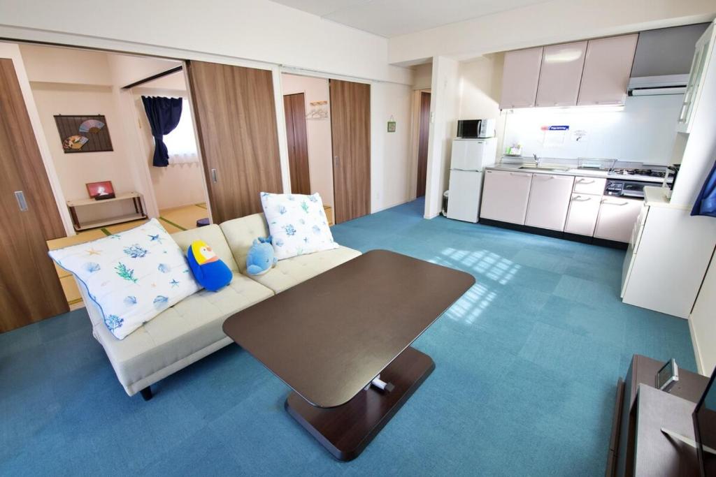 a living room with a couch and a table at はなハウス 401 in Ginowan