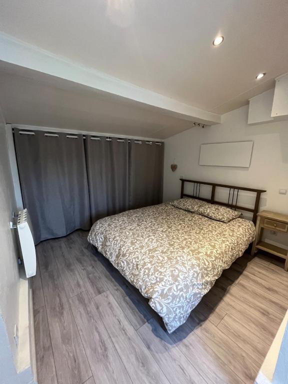 a bedroom with a bed and a wooden floor at Maisonnette chaleureuse, paisible & proche tram in Blanquefort