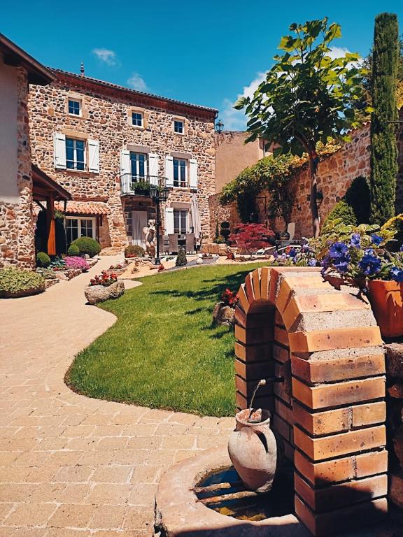 a stone house with a stone oven in a yard at Le clos fleuri in Saint-Gervazy