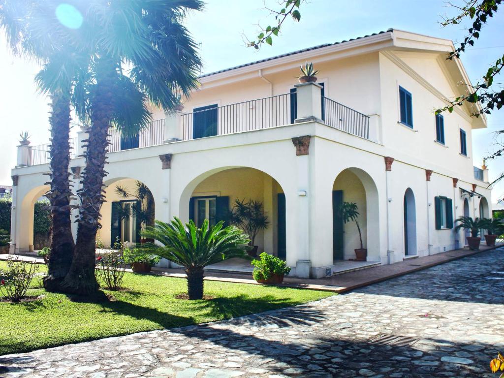 een groot wit huis met palmbomen ervoor bij Villa Glicini in Lamezia Terme