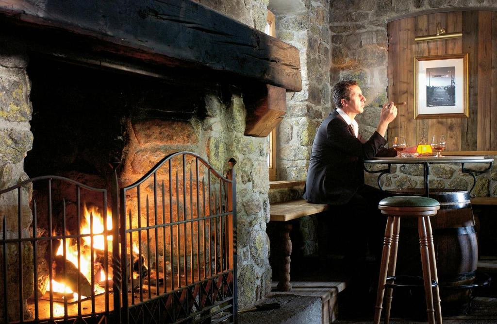 a man in a suit standing in front of a fireplace at Hotel Tyrolerhof in Sölden