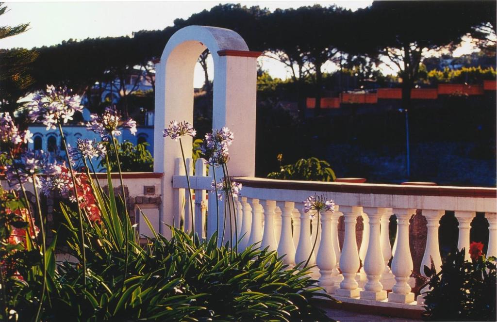 a white fence in front of a garden with flowers at Villa Brigio in Forio d'Ischia
