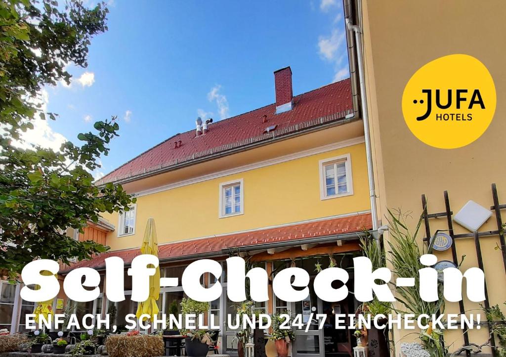 a building with a sign that reads self check in emerald schledel at JUFA Hotel Seckau - Self Check-in in Seckau