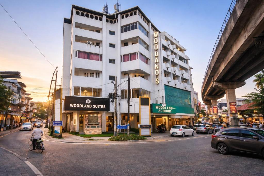 a tall white building on a city street with cars at WoodLand Suites in Cochin