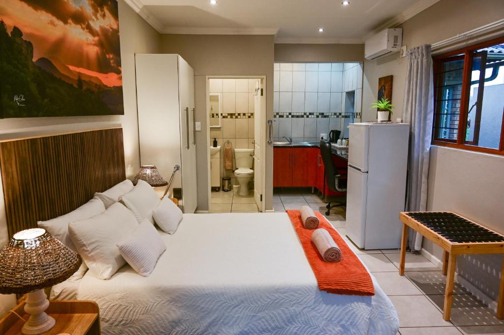 a bedroom with a large white bed and a kitchen at Son Heuwel B&B room in Nelspruit