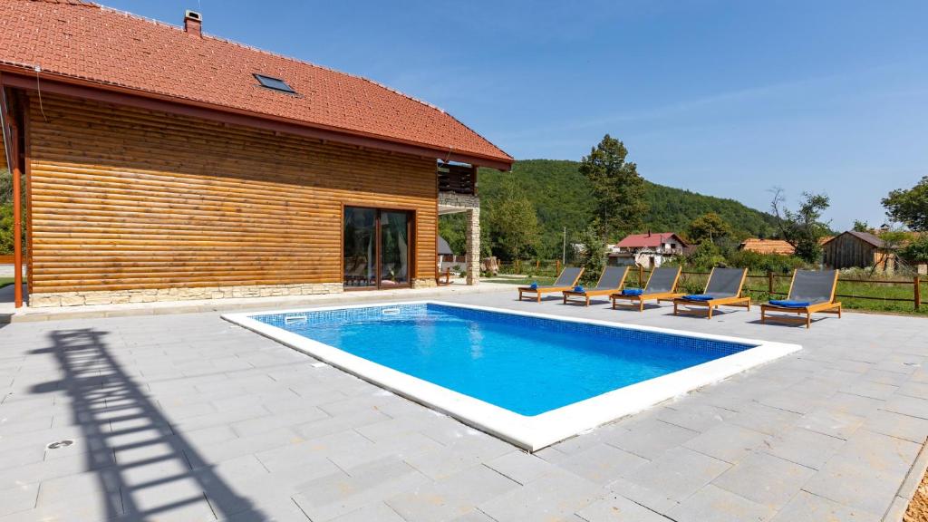 a swimming pool with chairs and a house at Villa D-Ika by Villas Guide in Brušane