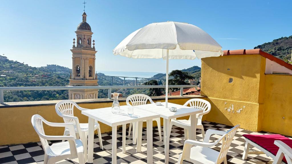 a white table with chairs and an umbrella on a balcony at Garibaldi by LigurianLife in Vallebona