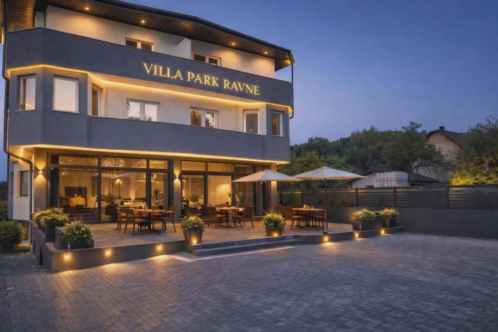 a building with a patio with tables and umbrellas at Villa Park Ravne in Visoko