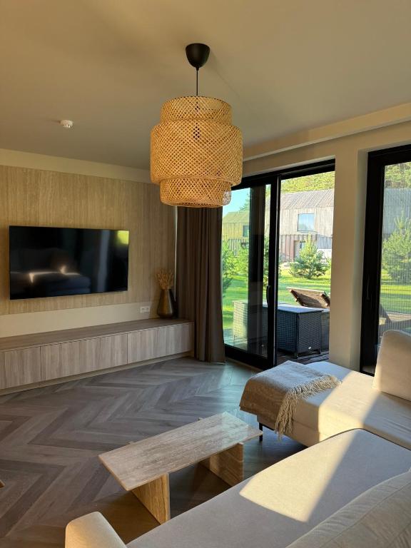 a living room with a couch and a tv at Luxury Seaside Home Papės Jūra in Pape