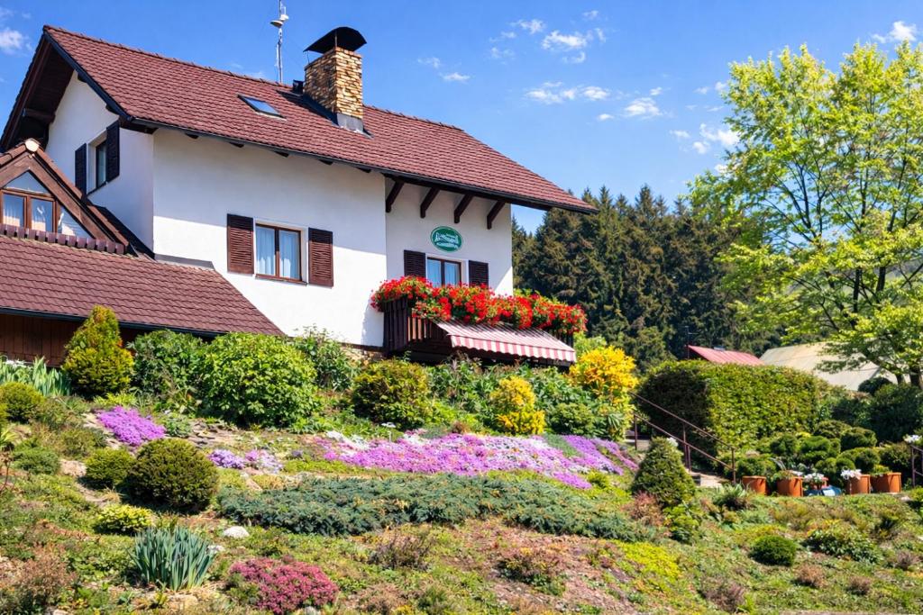a house with flowers in front of it at Pension a apartmány Hanna in Železná Ruda