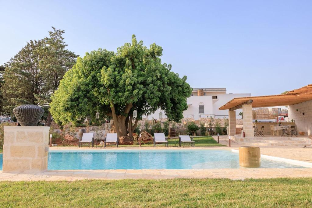a swimming pool in a yard with a tree at Masseria il Vignale in Ostuni