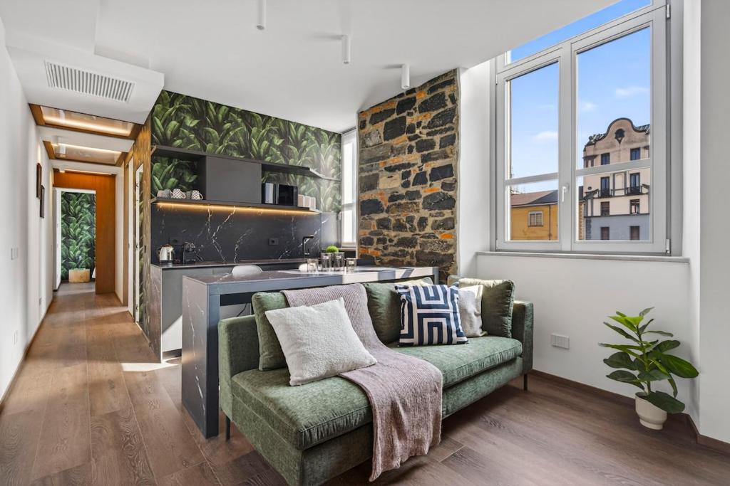a living room with a green couch and a kitchen at Appartamento Porta Torre - Porta Torre-Centro in Como