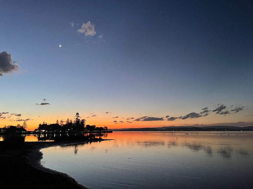 a sunset over a body of water with the sky at Lake Macquarie holidays in Marks Point