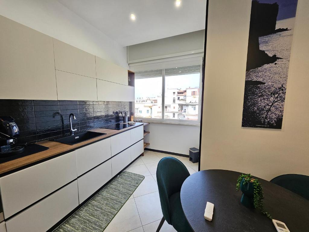 a kitchen with white cabinets and a table and a window at Cerasè Apartment in center-Sorrento Coast in Vico Equense