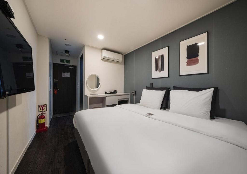 a bedroom with a large white bed and a television at Myeongdong Chungmuro Youngin Hotel in Seoul