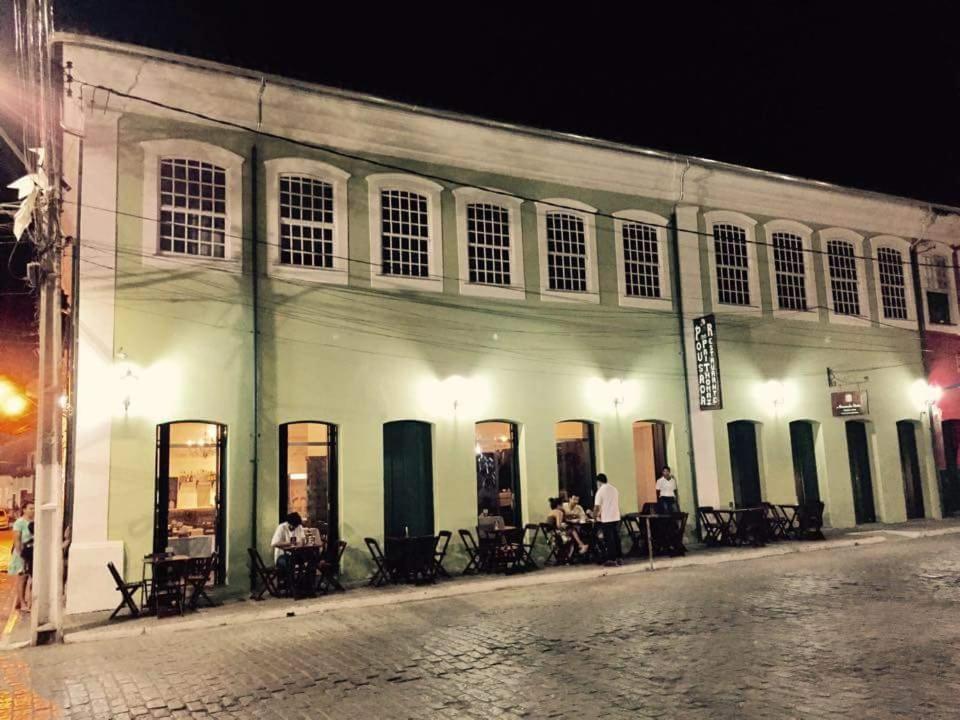 een groep mensen die aan tafels buiten een gebouw zitten bij Pousada Pai Thomaz in Cachoeira