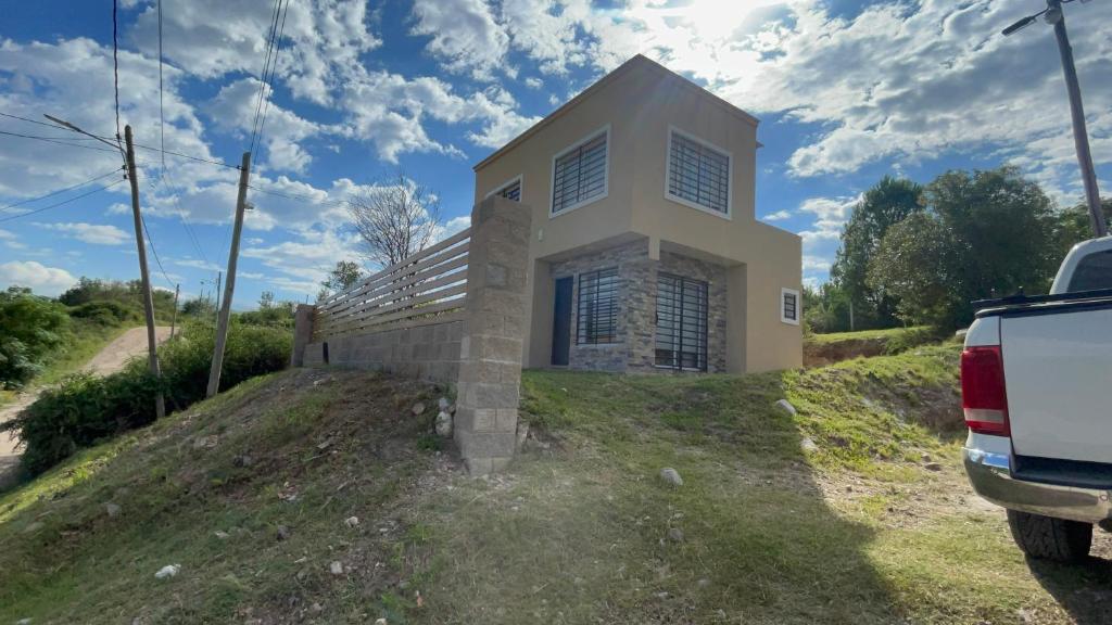 a house on a hill with a car parked in front at Las Pirquitas Villa Giardino in Huerta Grande