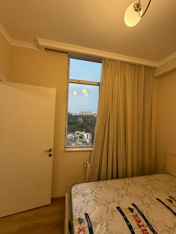 a bedroom with a bed and a large window at welcome apartment in Itʼkhvisi