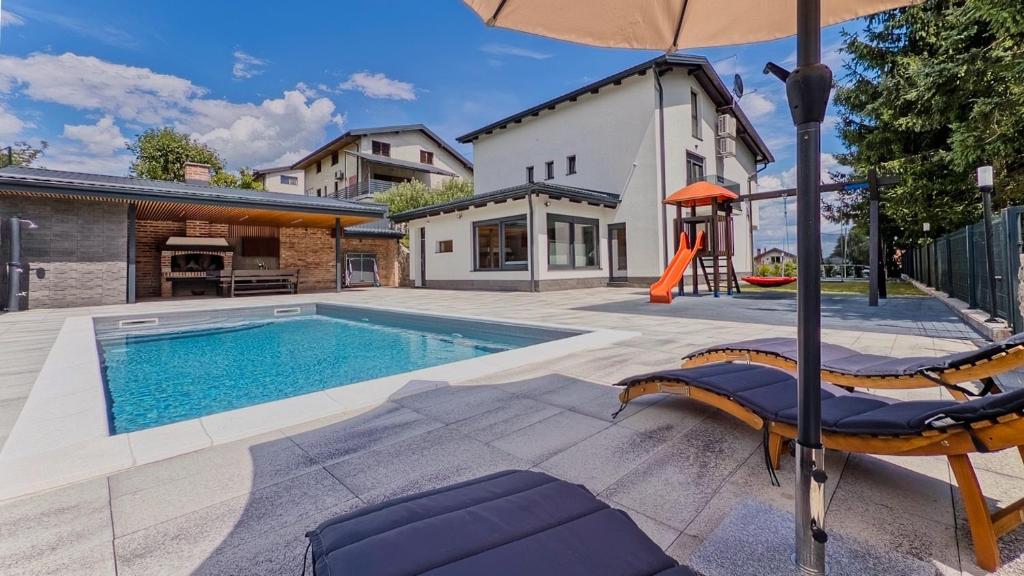 a swimming pool with two chairs and an umbrella at Villa Tia by Villas Guide in Karlovac