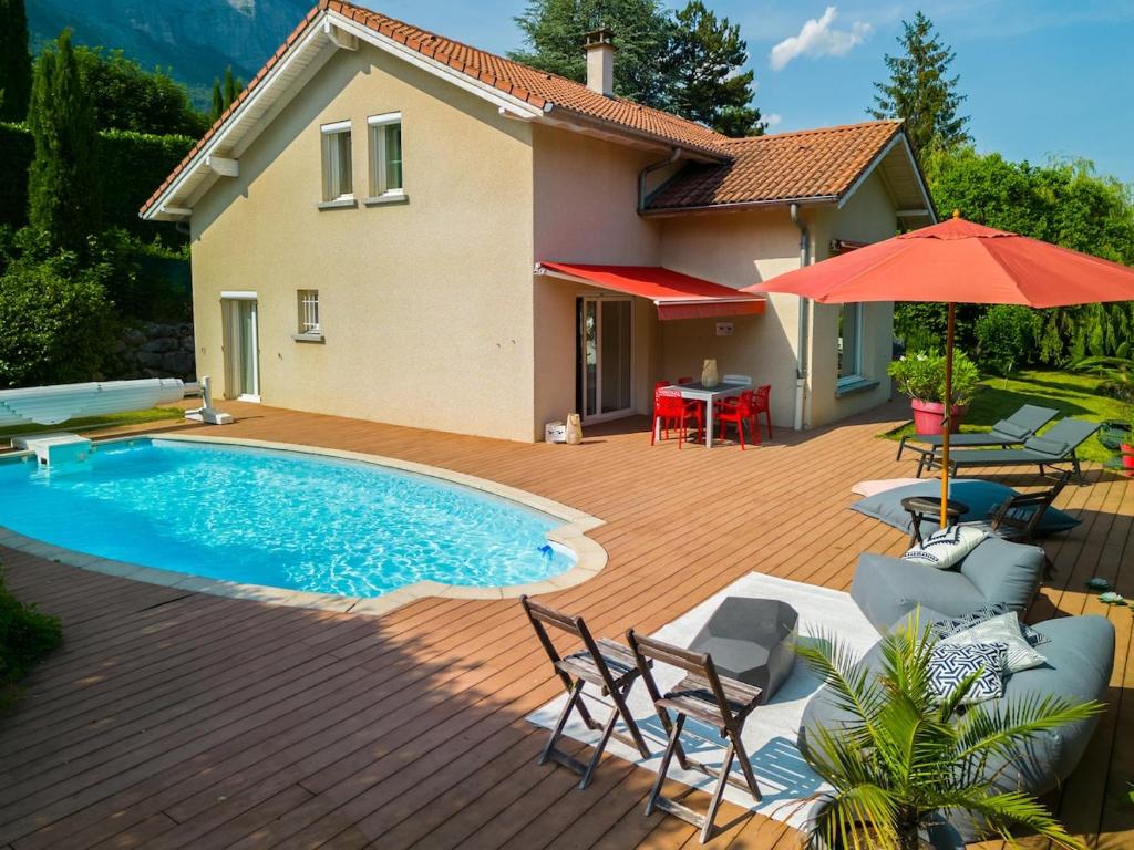 a patio with a pool and chairs and a house at Villa Galante in Meylan