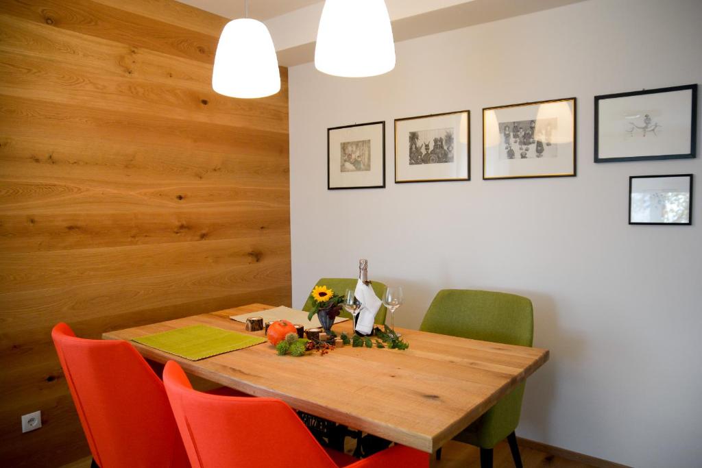 ein Esszimmer mit einem Holztisch und orangefarbenen Stühlen in der Unterkunft Spa & Wellness Apartment Gerda in Grinzens