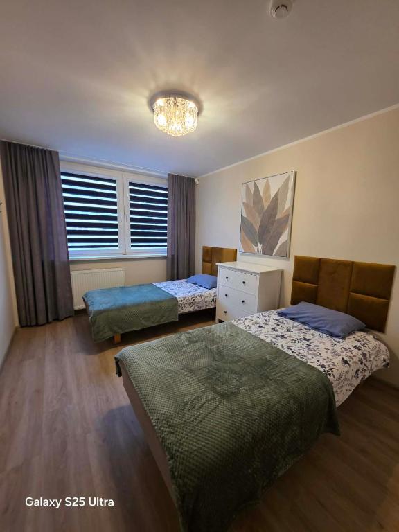 a bedroom with two beds and a chandelier at D20 apartamentai in Mažeikiai