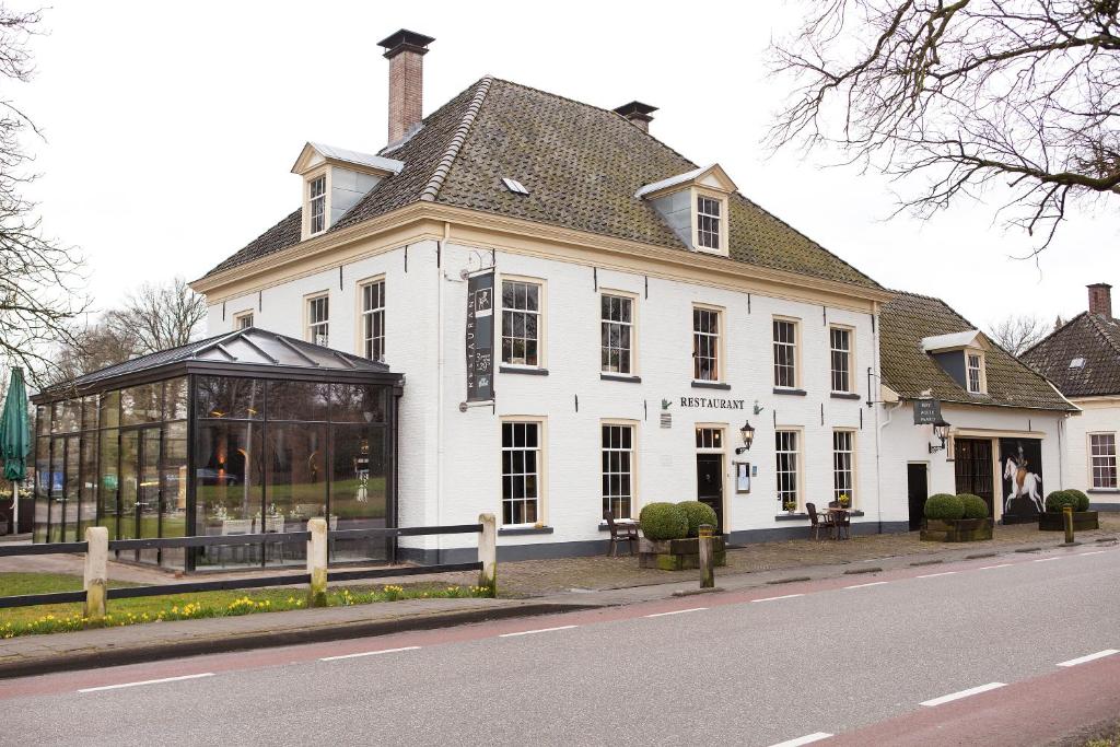 een groot wit gebouw met een serre naast een straat bij Hotel Restaurant Het Witte Paard in Delden