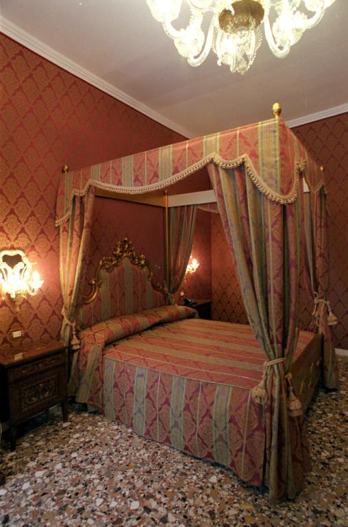 a bedroom with a canopy bed and a chandelier at Casa Pisani Canal in Venice