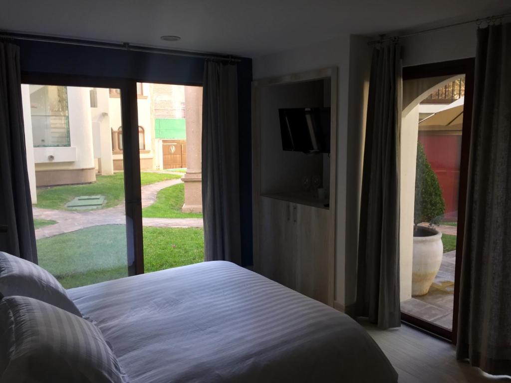 a bedroom with a bed and a window with a tv at Suites Casa Mateo San Miguel Allende in San Miguel de Allende