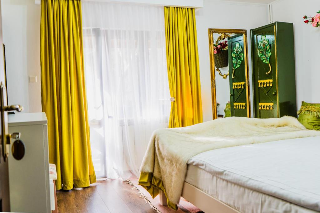 a bedroom with yellow curtains and a bed at SemiLuna in Buşteni