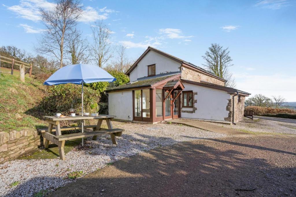 a picnic table with an umbrella in front of a cottage at 2 Bed in Risca oc-b35977 in Risca