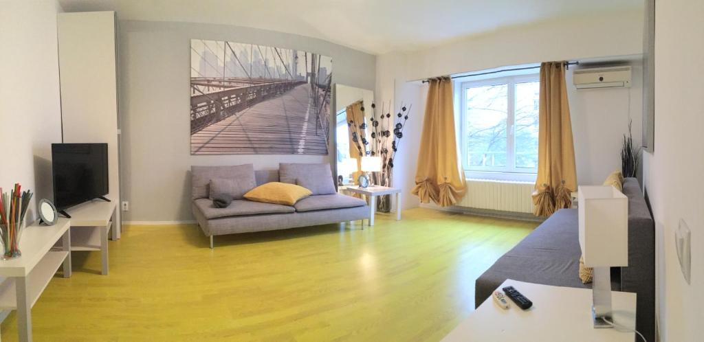 een woonkamer met een bank en een tv bij Green Apartment in Boekarest