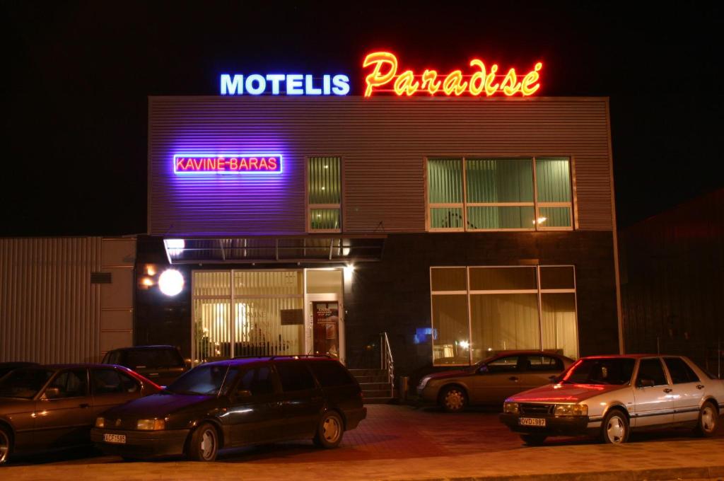 un bâtiment avec des voitures garées dans un parking la nuit dans l'établissement Motel Paradise, à Vilnius