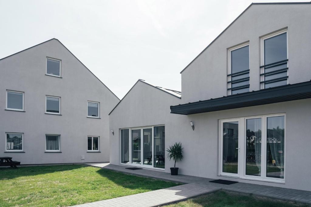 a white house with large windows and a yard at Słoneczna Bryza - domek, pokoje i apartamenty in Gąski