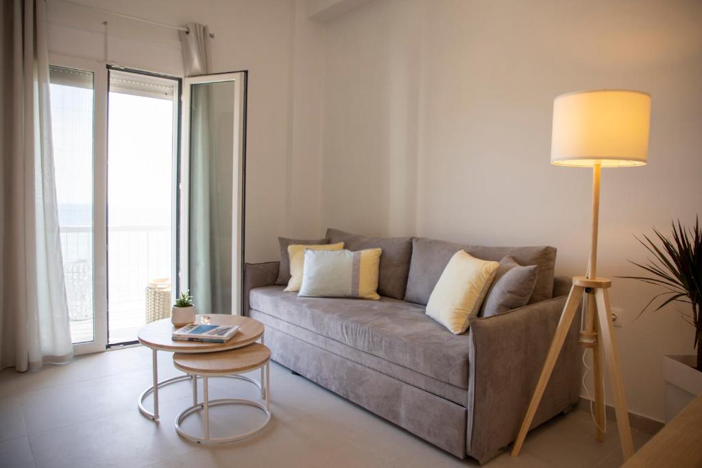 a living room with a couch and a table and a lamp at Infinite Blue Suites in Agia Marina Aegina