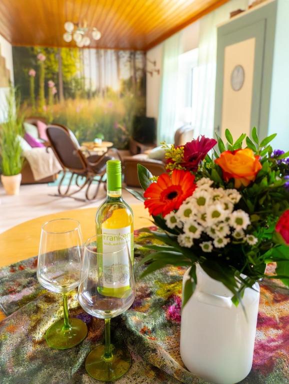 a table with a bottle of wine and a vase of flowers at Elfriedes' Ferienhäuschen in Marktschorgast