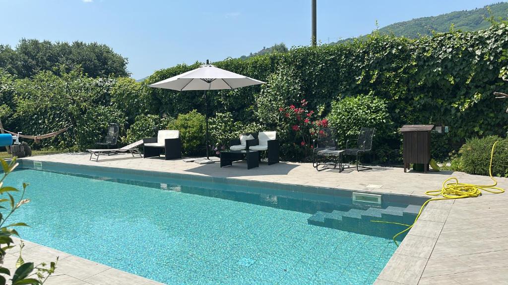 a swimming pool with an umbrella and chairs and tables at Casa Hydrangea con piscina e giardino in Bagni di Lucca