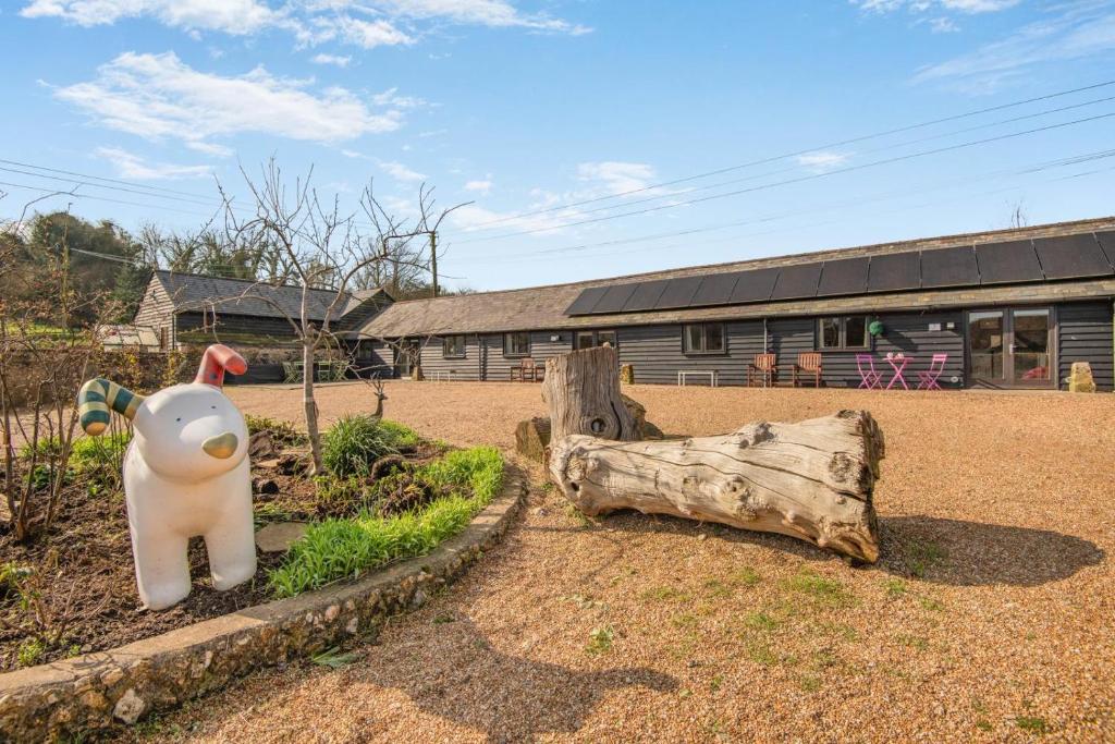 a toy cow sitting in a yard next to a log at 2 Bed in Hastingleigh oc-c36343 in Hastingleigh