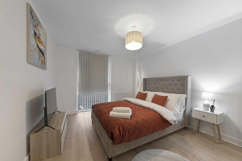 a white bedroom with a bed and a television at Alaska apartmans in London