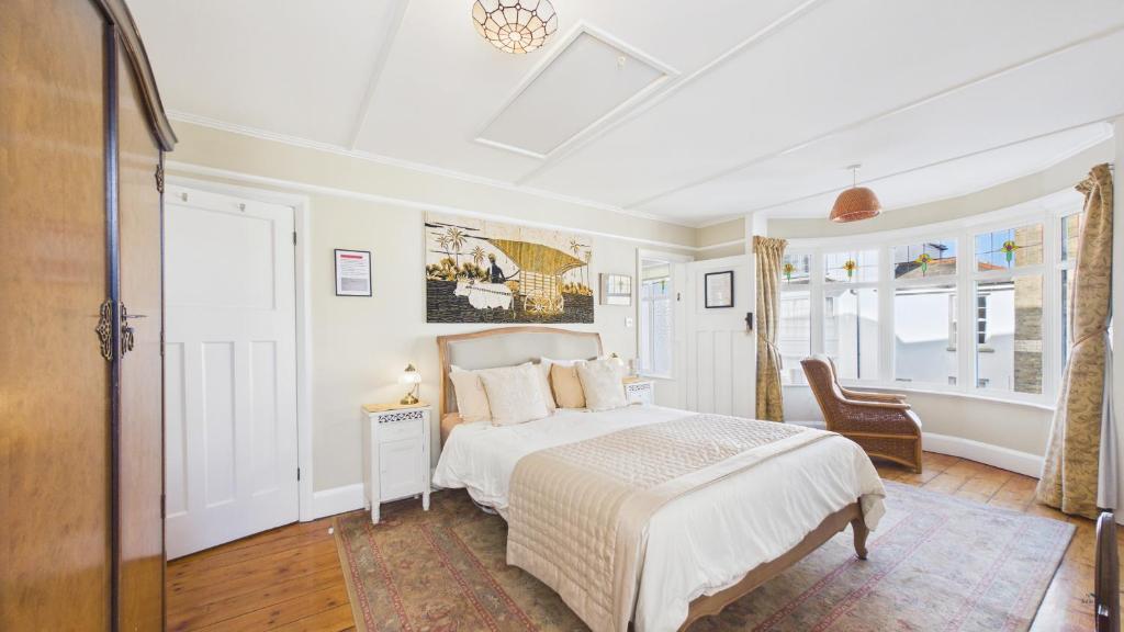 a white bedroom with a bed and a chair at Room with a View at Anchor Down Cottage in Ryde