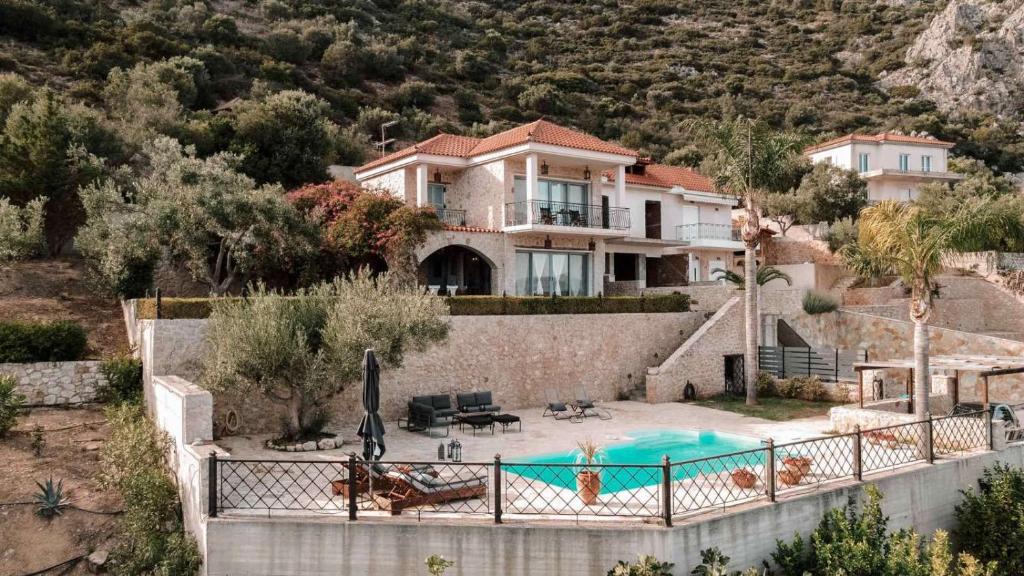 a house with a swimming pool in front of a mountain at Lilian Horizon in Tolo