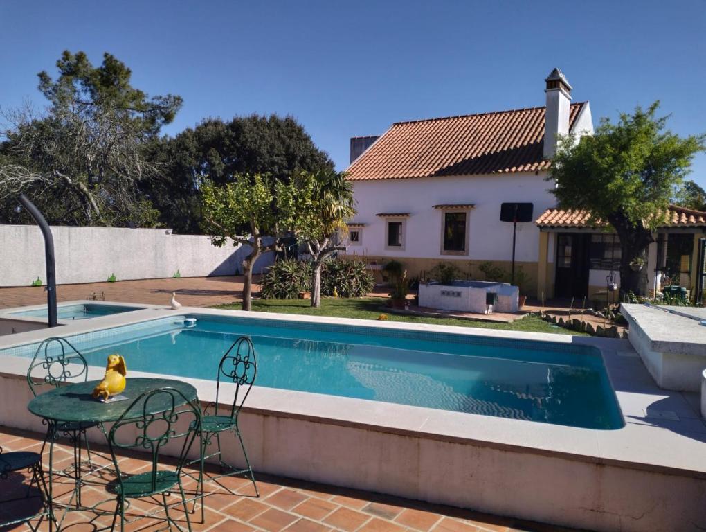 a pool with a table and chairs next to a house at Casa dos Avós in Parceiros da Igreja