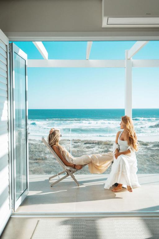 a bride and groom sitting in a chair at the beach at Jonesy's Place on the Beach in Yzerfontein