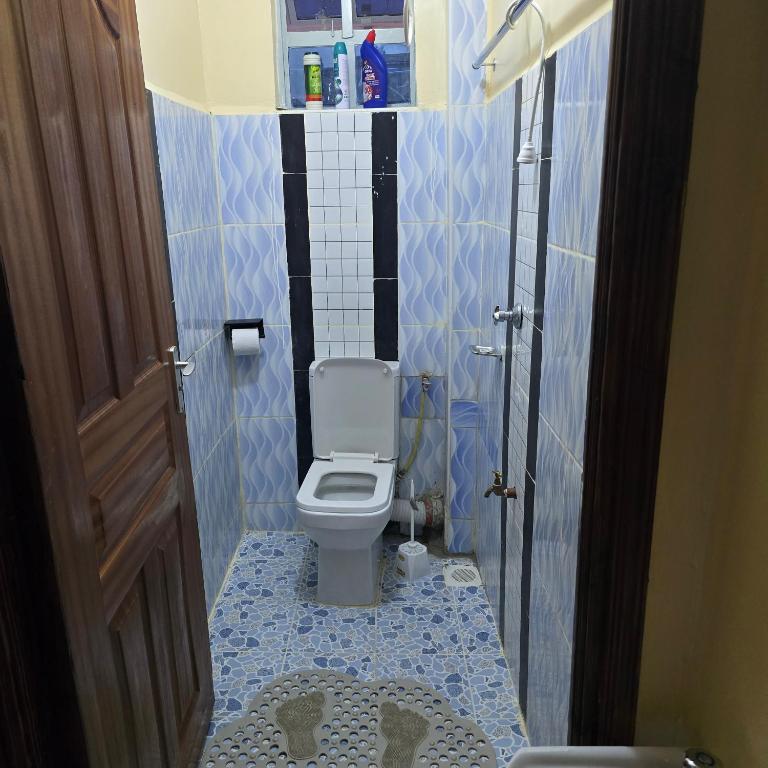 a bathroom with a toilet with a blue tiled floor at Sing' Homes in Eldoret