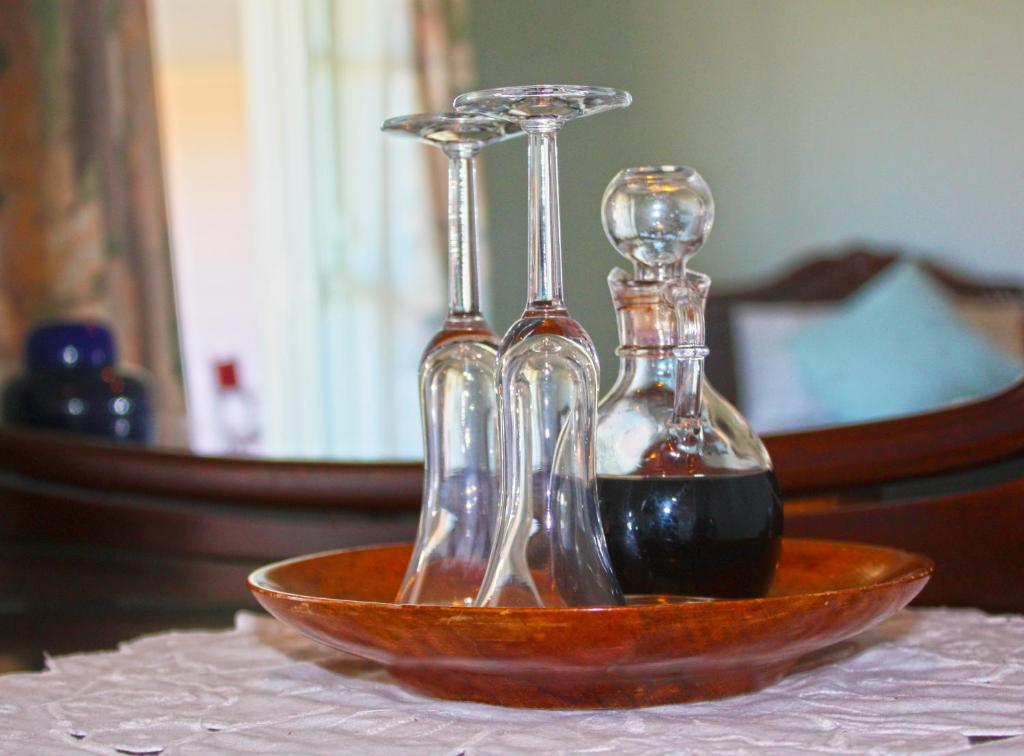 twee glazen flessen in een kom op een tafel bij Matakohe House in Matakohe
