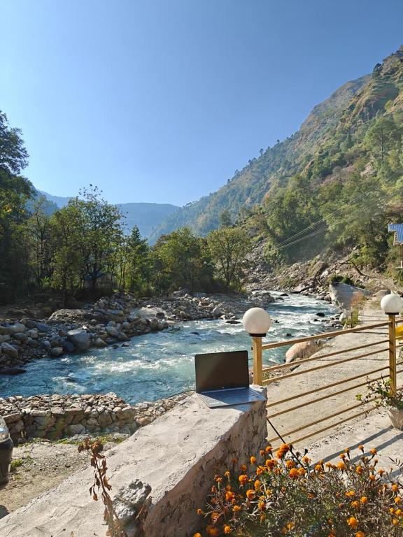 a laptop sitting on a bench next to a river at Nirvana River Nest in Sainj